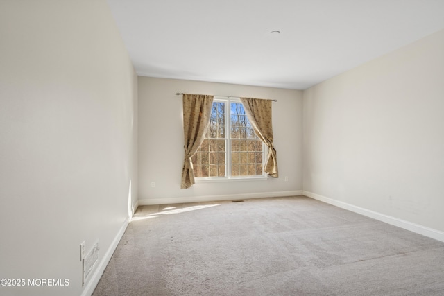 empty room featuring carpet floors, visible vents, and baseboards