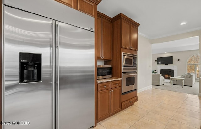 kitchen featuring light tile patterned floors, brown cabinetry, crown molding, and built in appliances