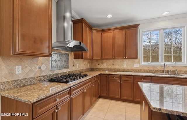 kitchen with light tile patterned floors, light stone countertops, wall chimney range hood, stainless steel gas cooktop, and a sink