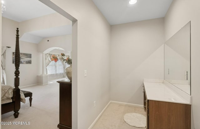 bathroom with vaulted ceiling, vanity, and baseboards