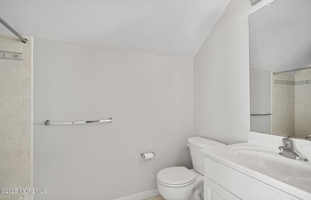 bathroom featuring tiled shower, vaulted ceiling, vanity, and toilet