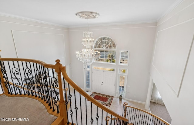 entrance foyer featuring a high ceiling, crown molding, baseboards, and an inviting chandelier