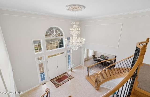 entryway with stairway, baseboards, a chandelier, and crown molding