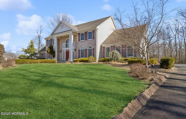 neoclassical / greek revival house featuring a front lawn and brick siding