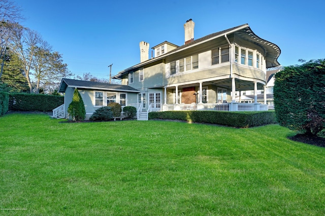 rear view of house featuring french doors, a lawn, and a chimney