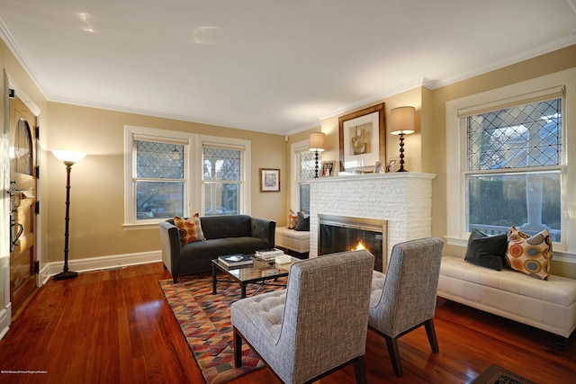 living room featuring ornamental molding, a brick fireplace, hardwood / wood-style flooring, and baseboards