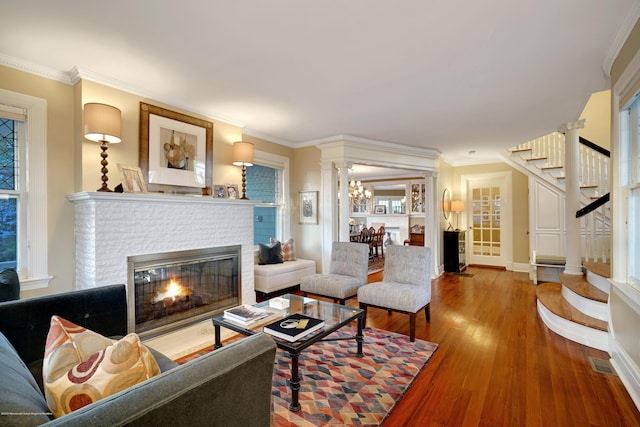 living room featuring stairs, a fireplace, ornamental molding, and wood finished floors