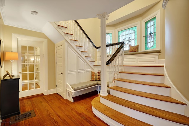 staircase with baseboards, crown molding, visible vents, and wood finished floors