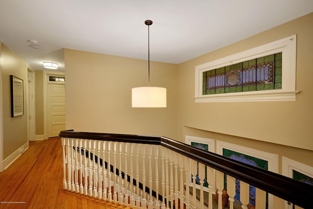 hall with baseboards, an upstairs landing, and wood finished floors