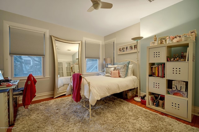 bedroom with ceiling fan, wood finished floors, and baseboards