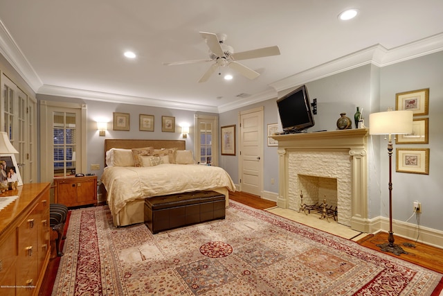 bedroom featuring ornamental molding, recessed lighting, a stone fireplace, and wood finished floors