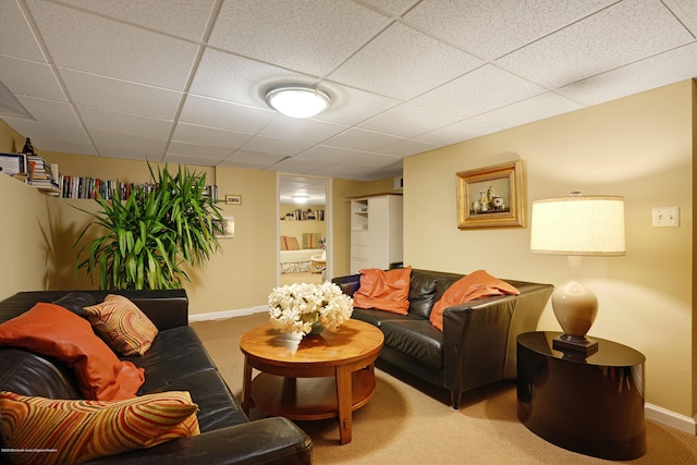 living area with carpet floors, a paneled ceiling, and baseboards