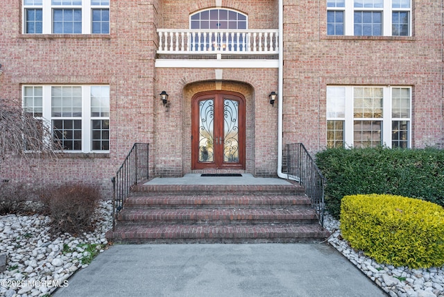 doorway to property with french doors, brick siding, and a balcony