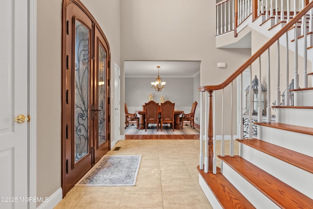 entryway with crown molding, stairway, a high ceiling, a chandelier, and tile patterned floors