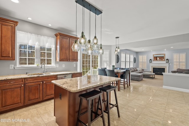 kitchen featuring light stone counters, recessed lighting, a fireplace, a kitchen island, and a sink