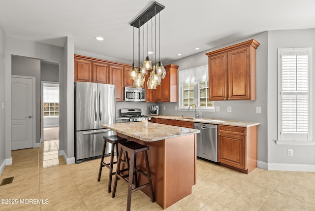 kitchen with stainless steel appliances, brown cabinetry, a sink, and a healthy amount of sunlight