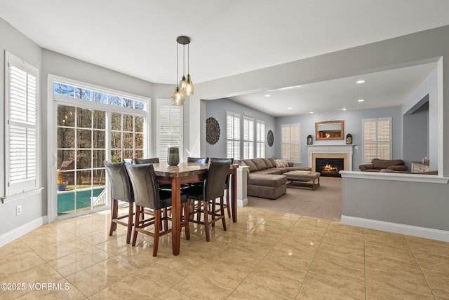 tiled dining room featuring recessed lighting, a warm lit fireplace, and baseboards