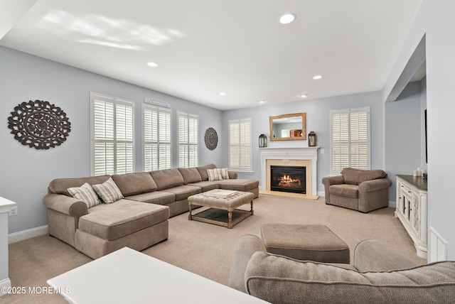 carpeted living area featuring a warm lit fireplace, a healthy amount of sunlight, visible vents, and recessed lighting