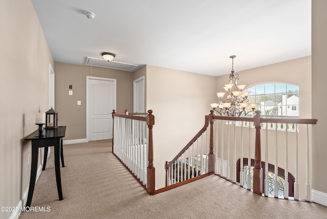 hallway featuring carpet floors, an inviting chandelier, attic access, an upstairs landing, and baseboards