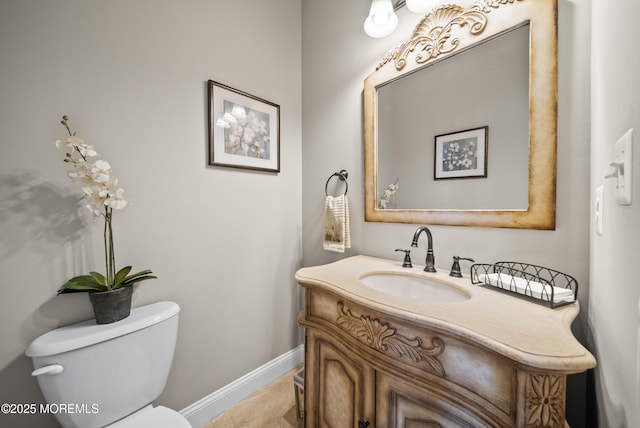 bathroom with toilet, baseboards, and vanity