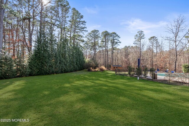 view of yard featuring a forest view, fence, and a fenced in pool