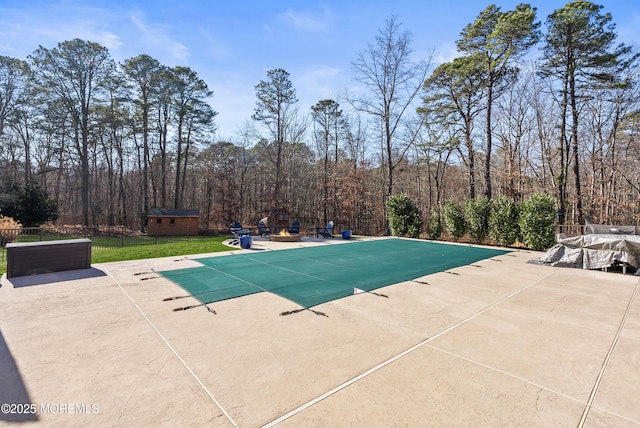 view of pool with a patio, fence, a wooded view, a covered pool, and an outdoor structure