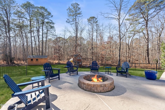 view of patio with an outdoor fire pit, a view of trees, an outbuilding, fence, and a playground