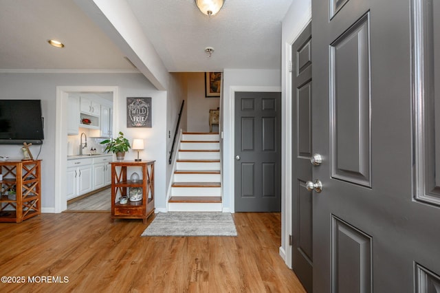 entryway featuring stairs, light wood-type flooring, and baseboards