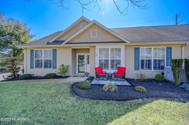 ranch-style house with a shingled roof, a patio, and a front yard