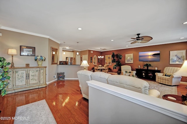 living room with recessed lighting, ceiling fan with notable chandelier, wood finished floors, baseboards, and ornamental molding