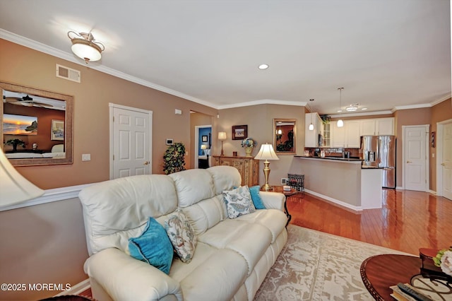 living room with ornamental molding, light wood-type flooring, visible vents, and recessed lighting