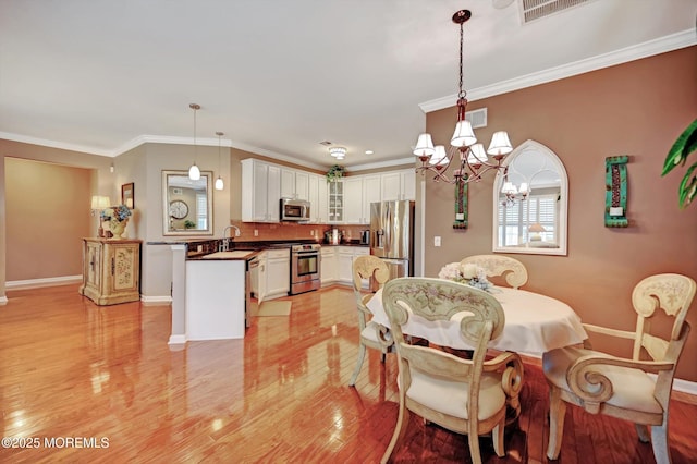 dining area featuring ornamental molding, visible vents, light wood-style flooring, and baseboards