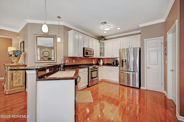 kitchen with light wood finished floors, visible vents, appliances with stainless steel finishes, a peninsula, and crown molding