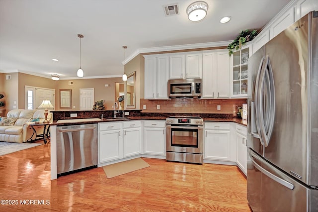 kitchen featuring visible vents, glass insert cabinets, open floor plan, stainless steel appliances, and a sink