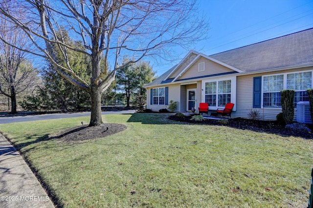 ranch-style home featuring a front lawn and roof with shingles