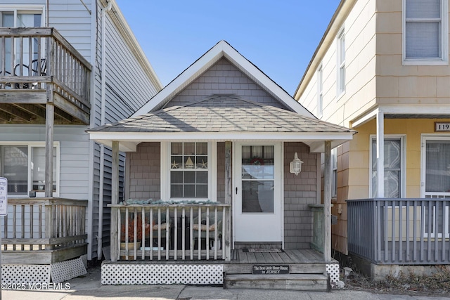 view of exterior entry featuring a porch and a shingled roof