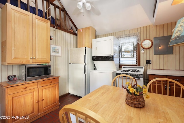 kitchen featuring white appliances, electric panel, brick floor, ceiling fan, and stacked washer / dryer