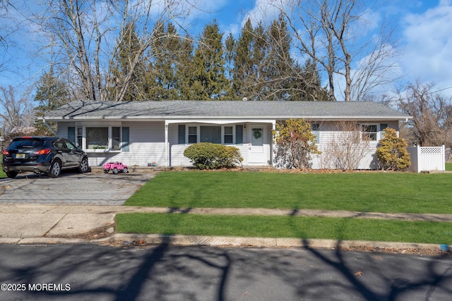 ranch-style house with roof with shingles, fence, and a front yard