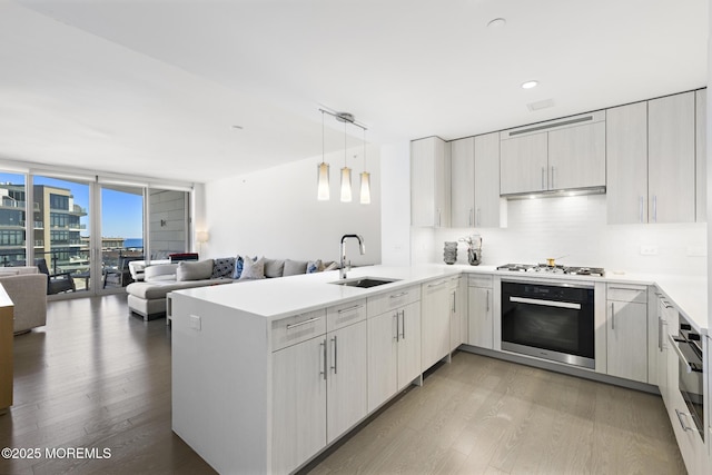 kitchen featuring a sink, oven, floor to ceiling windows, under cabinet range hood, and open floor plan