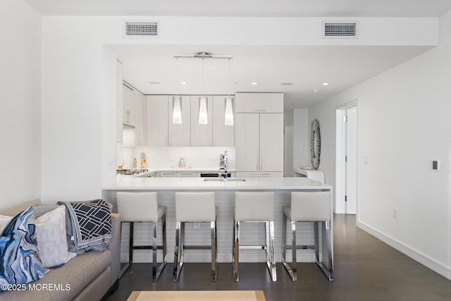 kitchen with visible vents, light countertops, a kitchen bar, and a sink