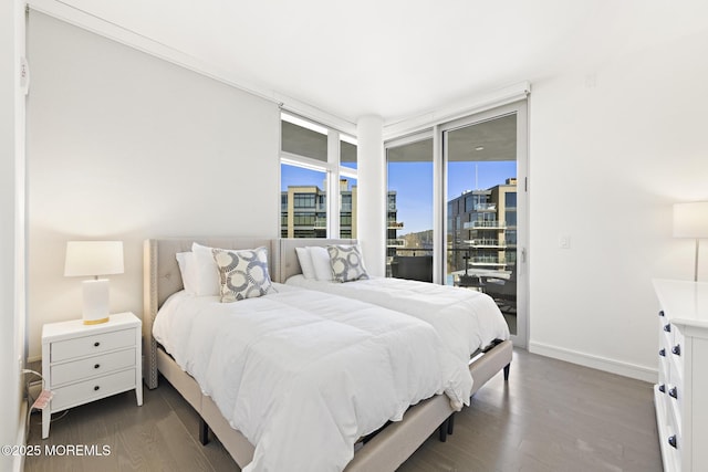 bedroom featuring access to exterior, a view of city, dark wood-style floors, and baseboards