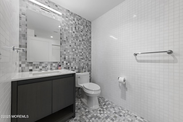 bathroom with tile patterned flooring, toilet, tile walls, and vanity