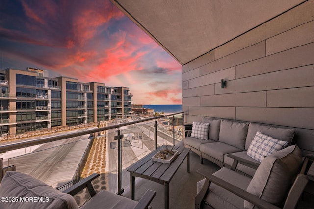 balcony at dusk featuring a water view and an outdoor hangout area