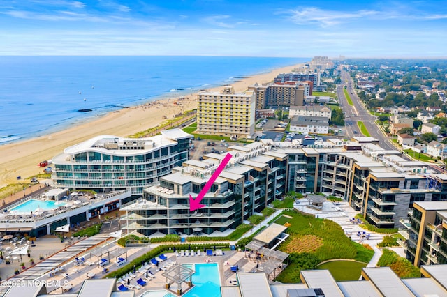 drone / aerial view with a water view, a view of city, and a beach view