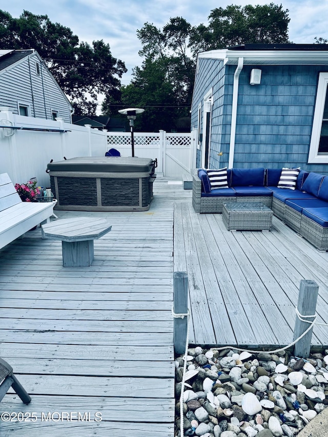 wooden deck with a covered hot tub, outdoor lounge area, and fence