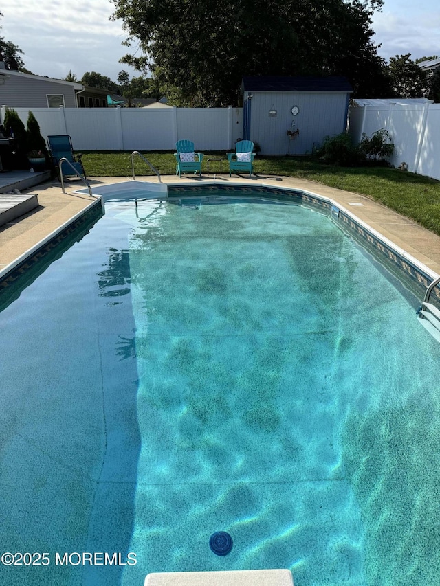 view of pool featuring an outbuilding, a storage shed, a fenced backyard, and a fenced in pool