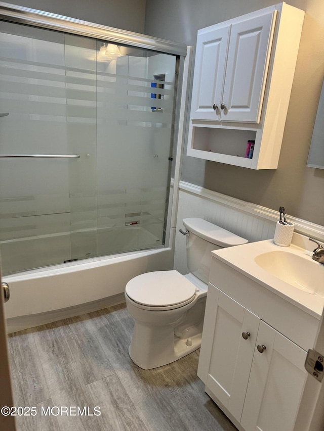 full bathroom featuring vanity, shower / bath combination with glass door, wood finished floors, and toilet