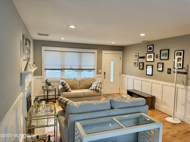 living area with a fireplace, light wood finished floors, recessed lighting, visible vents, and a baseboard heating unit