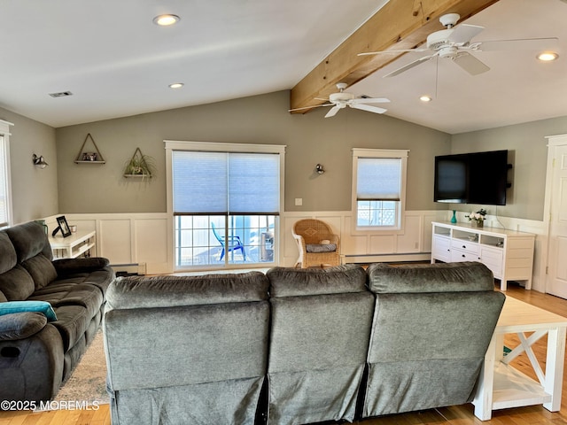 living area featuring vaulted ceiling with beams, a wainscoted wall, wood finished floors, and visible vents