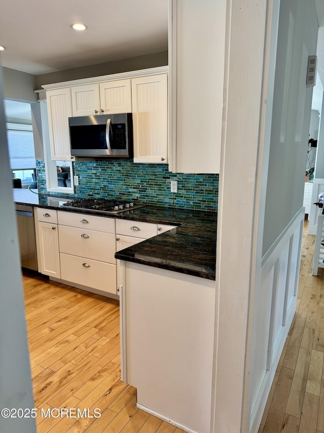 kitchen with white cabinets, stainless steel appliances, light wood-style floors, backsplash, and recessed lighting